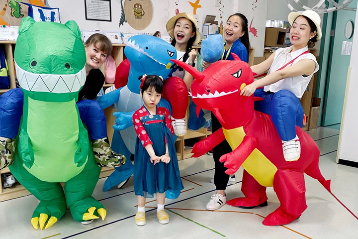 Teachers with inflatable dinosaur costumes and young student